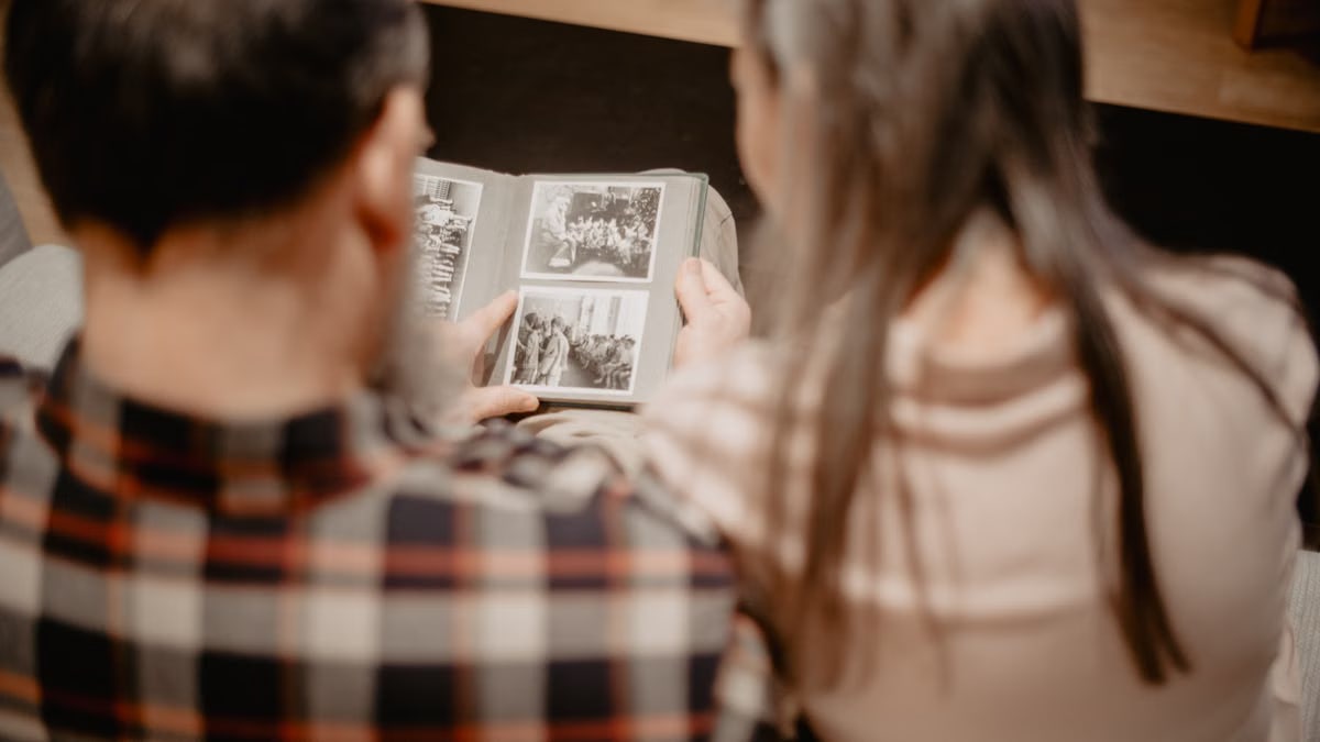 A couple reminisces while looking through a family photo album, capturing warm memories indoors.